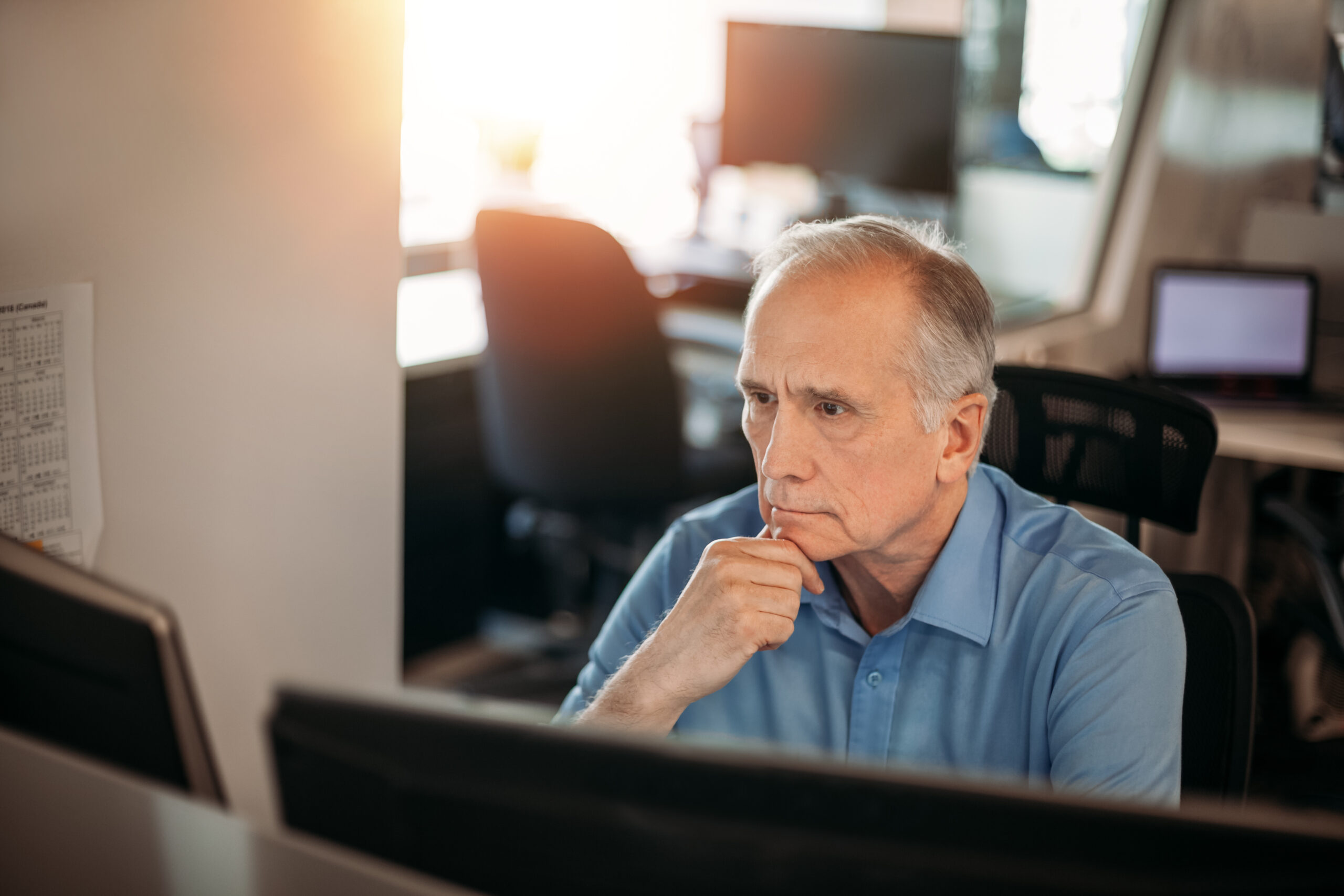 Senior businessman contemplating data on computer screen to make decisions in office